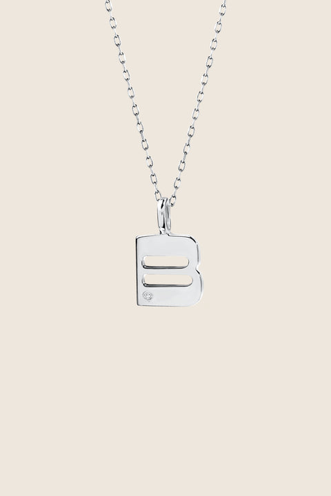 A delicate letter B pendant necklace inlaid with a natural diamond of 0.007 ct and 1.2 mm diameter. Suspended on a 50 cm chain, this timeless initial design offers a personal and elegant way to celebrate someone special. A refined keepsake that never goes out of style. Discover meaningful jewelry by UMIAR jewelry.