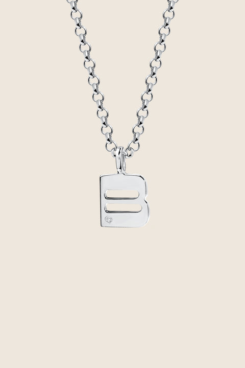 A delicate letter B pendant necklace inlaid with a natural diamond of 0.007 ct and 1.2 mm diameter. Suspended on a 50 cm chain, this timeless initial design offers a personal and elegant way to celebrate someone special. A refined keepsake that never goes out of style. Discover meaningful jewelry by UMIAR jewelry.