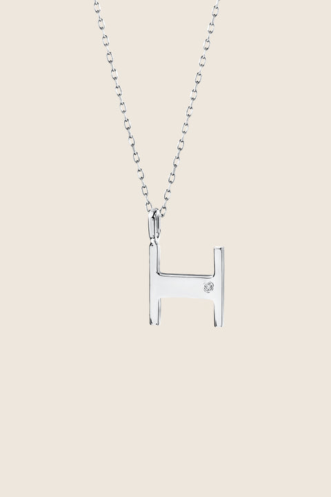 A delicate letter H pendant necklace inlaid with a natural diamond of 0.007 ct and 1.2 mm diameter. Suspended on a 50 cm chain, this timeless initial design offers a personal and elegant way to celebrate someone special. A refined keepsake that never goes out of style. Discover meaningful jewelry by UMIAR jewelry.
