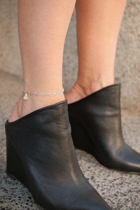 A delicate chain anklet finished with a shell pendant measuring 11 x 7 mm. Designed to enhance summer styling, this adjustable anklet of approximately 26 cm adds a subtle, marine-inspired accent that highlights the ankle with effortless elegance. A perfect companion for warm-weather looks. Discover refined summer jewelry by UMIAR jewelry.
