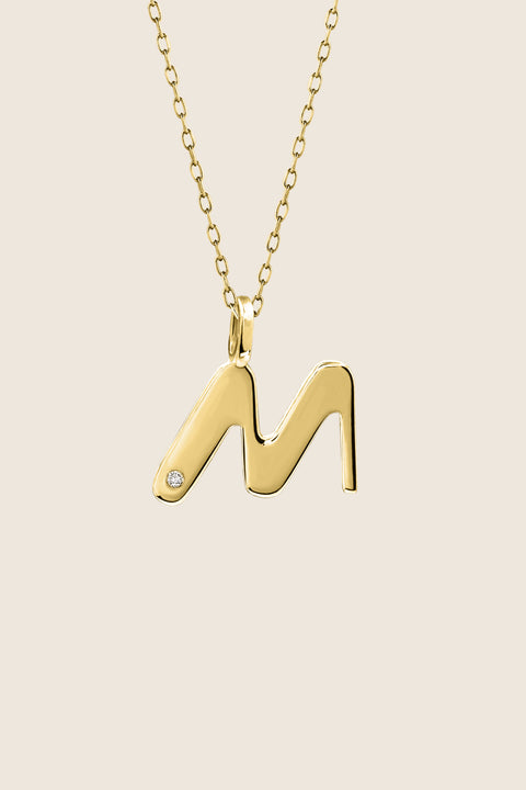 A delicate letter M pendant necklace inlaid with a natural diamond of 0.007 ct and 1.2 mm diameter. Suspended on a 50 cm chain, this timeless initial design offers a personal and elegant way to celebrate someone special. A refined keepsake that never goes out of style. Discover meaningful jewelry by UMIAR jewelry.