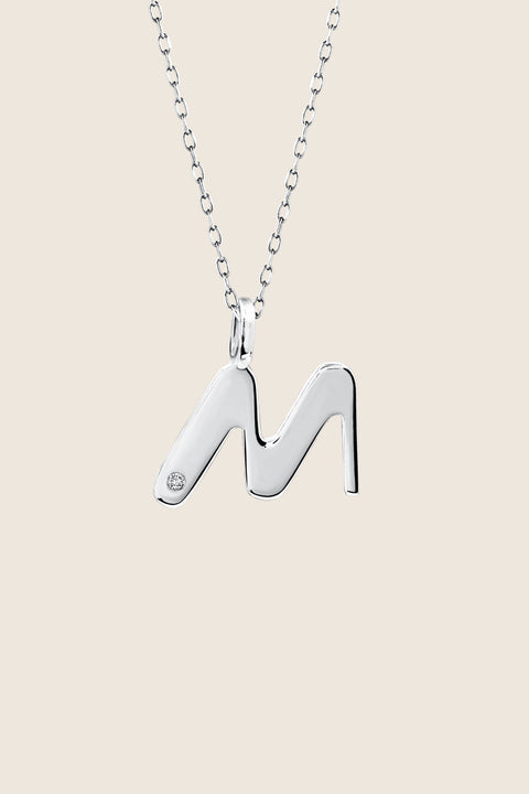A delicate letter M pendant necklace inlaid with a natural diamond of 0.007 ct and 1.2 mm diameter. Suspended on a 50 cm chain, this timeless initial design offers a personal and elegant way to celebrate someone special. A refined keepsake that never goes out of style. Discover meaningful jewelry by UMIAR jewelry.