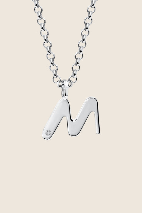 A delicate letter M pendant necklace inlaid with a natural diamond of 0.007 ct and 1.2 mm diameter. Suspended on a 50 cm chain, this timeless initial design offers a personal and elegant way to celebrate someone special. A refined keepsake that never goes out of style. Discover meaningful jewelry by UMIAR jewelry.