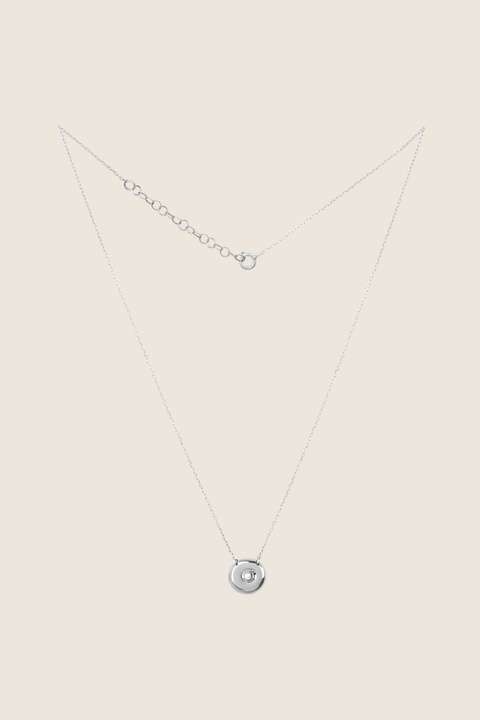 UMIAR jewellery presents an elegant pendant necklace with a natural pearl, handcrafted from 925 sterling silver. The round disc with a recessed pearl detail blends timeless style with a modern touch, symbolising femininity, closeness, and the cycles of life. Perfect for both everyday wear and special occasions. Discover it online today!