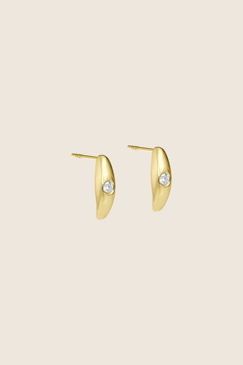 Elegant stud earrings featuring a natural diamond, handcrafted in 14k yellow gold. Their softly rounded setting and the diamond’s intense brilliance create a refined, timeless accent — an ideal gift and a sophisticated detail for both everyday and evening looks. Discover the quality of UMIAR jewelry and order online.