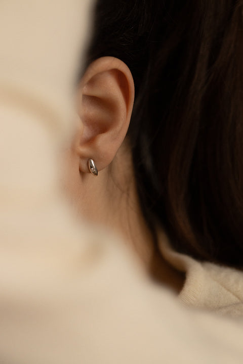 Elegant stud earrings featuring a natural diamond set in a softly rounded, delicate setting. The subtle brilliant-cut stone catches the eye with its intense sparkle, adding refined elegance to both everyday and evening looks. Discover the quality of UMIAR jewelry and order online.