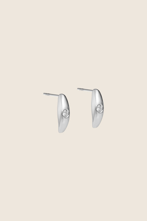 Elegant stud earrings featuring a natural diamond set in a softly rounded, delicate setting. The subtle brilliant-cut stone catches the eye with its intense sparkle, adding refined elegance to both everyday and evening looks. Discover the quality of UMIAR jewelry and order online.