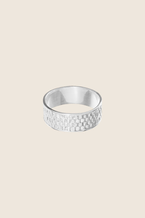 The striking RISTA band ring with a textured braided motif blends modern character with timeless elegance. Its wide form reflects the light beautifully, adding subtle dynamism to the hand. This design looks stunning on its own or paired with the Vintage Touche and BON-BON rings. Discover the unique style of UMIAR jewelry and order online.