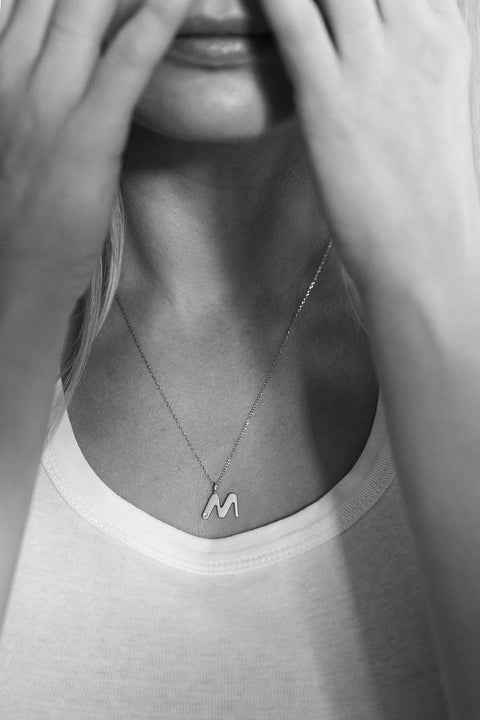A delicate letter M pendant necklace inlaid with a natural diamond of 0.007 ct and 1.2 mm diameter. Suspended on a 50 cm chain, this timeless initial design offers a personal and elegant way to celebrate someone special. A refined keepsake that never goes out of style. Discover meaningful jewelry by UMIAR jewelry.