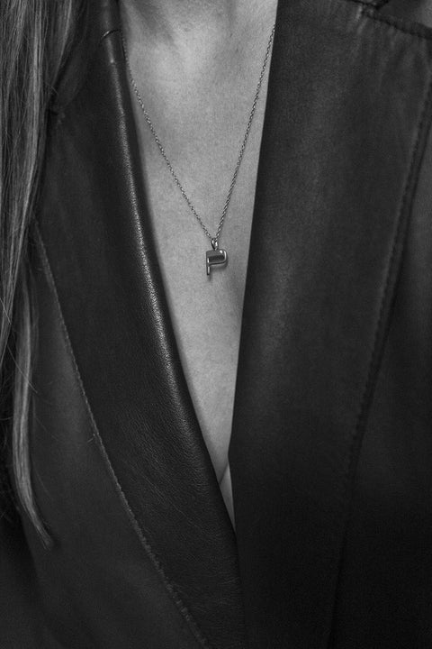 A delicate letter P pendant necklace inlaid with a natural diamond of 0.007 ct and 1.2 mm diameter. Suspended on a 50 cm chain, this timeless initial design offers a personal and elegant way to celebrate someone special. A refined keepsake that never goes out of style. Discover meaningful jewelry by UMIAR jewelry.