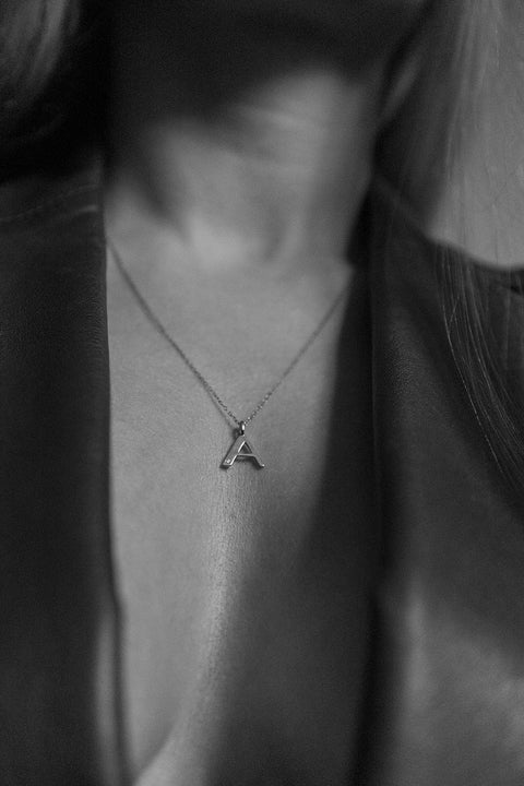 A delicate letter A pendant necklace inlaid with a natural diamond of 0.007 ct and 1.2 mm diameter. Suspended on a 50 cm chain, this timeless initial design offers a personal and elegant way to celebrate someone special. A refined keepsake that never goes out of style. Discover meaningful jewelry by UMIAR jewelry.
