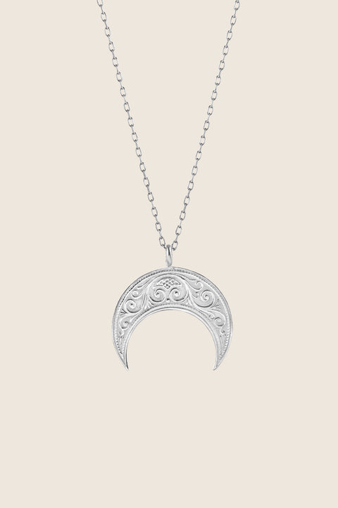 A lunula moon pendant inspired by ancient Roman symbolism, representing femininity and good fortune. Decoratively detailed and vertically proportioned, it is suspended on a 50 cm chain and measures 22 x 18 mm. A distinctive piece that combines history with contemporary elegance. Discover meaningful design by UMIAR jewelry.