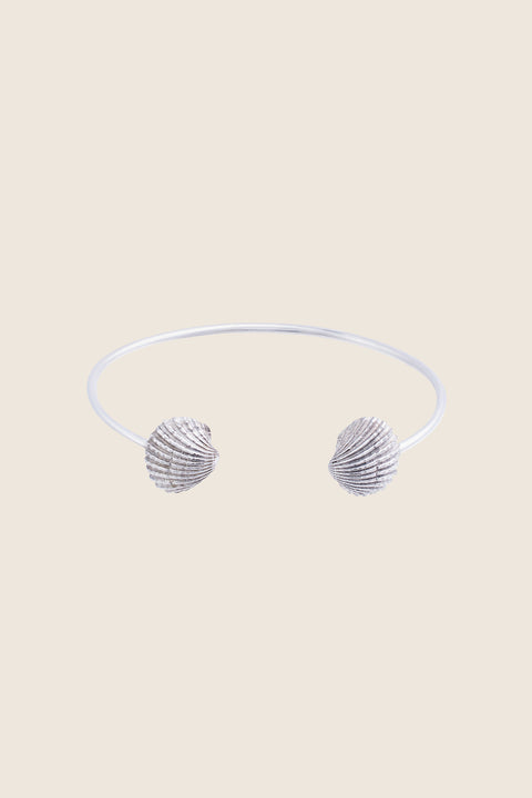 A rigid cuff bracelet adorned with realistic shell details that capture the essence of summer by the sea. Featuring shell elements measuring 15 × 13 mm, it blends decorative charm with classic elegance. Ideal for summer styling and refined everyday wear. Discover timeless seasonal design by UMIAR jewelry.