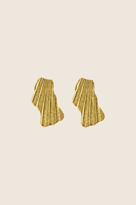 Elegant ear clips inspired by broken shells, designed as a summer statement in a refined form. Measuring 15 x 29 mm, they offer a stylish alternative to pierced earrings and add character to warm-weather looks. A sculptural accent that blends ease with elegance. Discover summer-ready design by UMIAR jewelry.