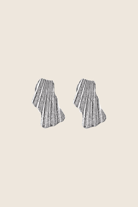 Elegant ear clips inspired by broken shells, designed as a summer statement in a refined form. Measuring 15 x 29 mm, they offer a stylish alternative to pierced earrings and add character to warm-weather looks. A sculptural accent that blends ease with elegance. Discover summer-ready design by UMIAR jewelry.
