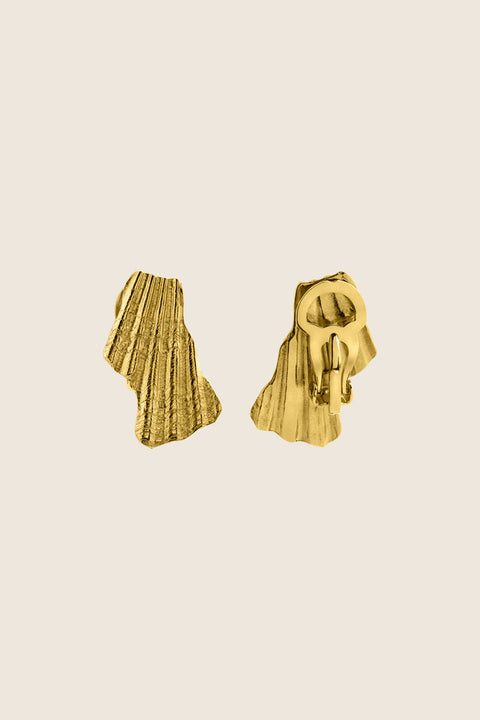 Elegant ear clips inspired by broken shells, designed as a summer statement in a refined form. Measuring 15 x 29 mm, they offer a stylish alternative to pierced earrings and add character to warm-weather looks. A sculptural accent that blends ease with elegance. Discover summer-ready design by UMIAR jewelry.