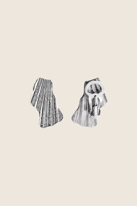 Elegant ear clips inspired by broken shells, designed as a summer statement in a refined form. Measuring 15 x 29 mm, they offer a stylish alternative to pierced earrings and add character to warm-weather looks. A sculptural accent that blends ease with elegance. Discover summer-ready design by UMIAR jewelry.
