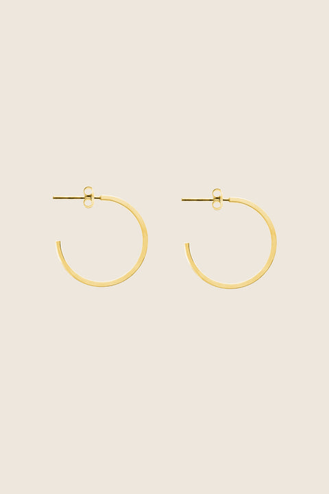 Delicate square-profile hoop earrings with a modern geometric character. Featuring a 23 mm diameter, they bring a contemporary edge to a classic form and can be worn alone or layered with ACTA MICRO. A timeless everyday essential. Discover refined minimalism by UMIAR jewelry.