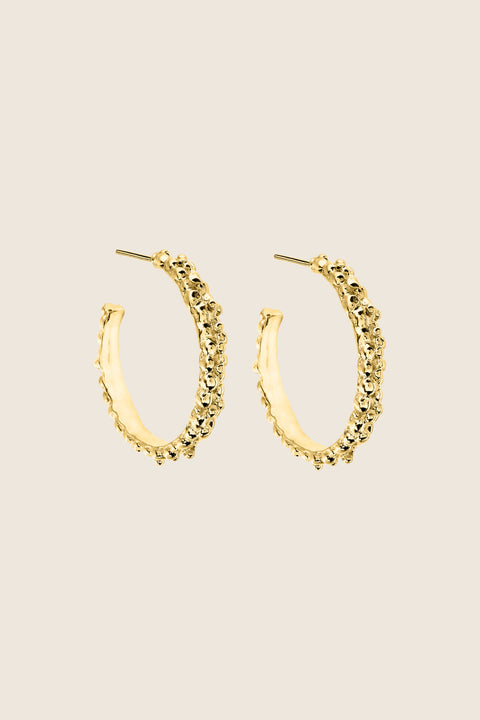 Large hoop earrings inspired by the sculptural surface of the moon, featuring a speckled, textured silver finish. With a 30 mm diameter, their irregular granulated structure reflects light beautifully, creating a bold yet elegant statement for evening wear. Discover expressive design by UMIAR jewelry.