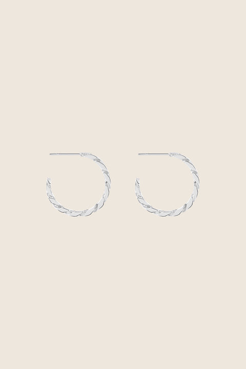 Hoop earrings inspired by the bold texture of a classic curb chain, featuring a 25 mm diameter. Combining 90s power dressing with modern elegance, this versatile design transitions seamlessly from day to night. A statement piece that adapts to every style. Discover confident design by UMIAR jewelry.