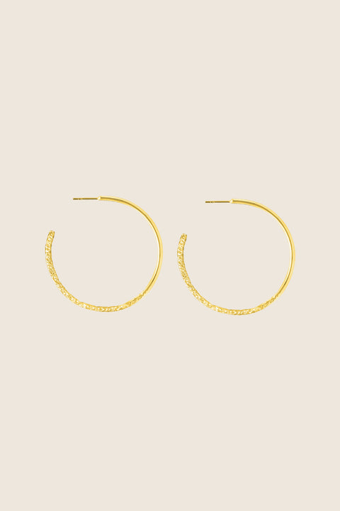 Hoop earrings with a distinctive evolving texture that shifts from hammered to smooth, polished finish. Featuring a bold 45 mm diameter, they offer an expressive yet elegant accent that enhances both minimalist and statement styling. Discover refined craftsmanship and modern design by UMIAR jewelry.