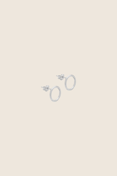 Minimal circle stud earrings set flat against the ear, designed for effortless everyday wear. With a 10 mm diameter, they suit business, casual, and sporty looks alike. A subtle yet distinctive detail that adapts to the ear’s natural geometry. Discover refined simplicity by UMIAR jewelry.
