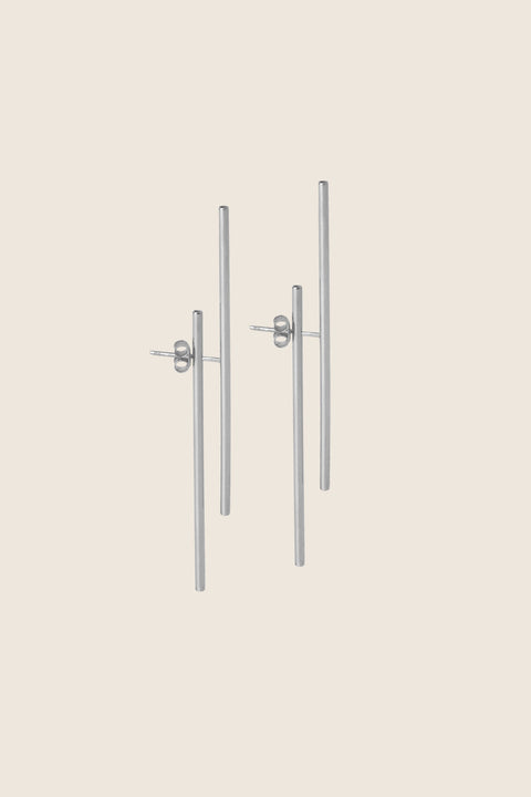 Extraordinary double-sided earrings featuring two dynamic straight lines and a distinctive layered construction. Composed of a front stud, back tube, and stopper, they create a modern, architectural statement that elevates any look. Discover contemporary design and refined craftsmanship by UMIAR jewelry.