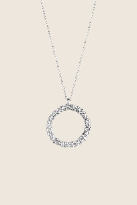 A circular pendant symbolizing perfection, crafted with a granulated, speckled silver texture inspired by the full moon. Suspended on a 50 cm silver chain, it works beautifully as a daily talisman or an elegant evening accessory. Discover cosmic elegance and timeless design by UMIAR jewelry.