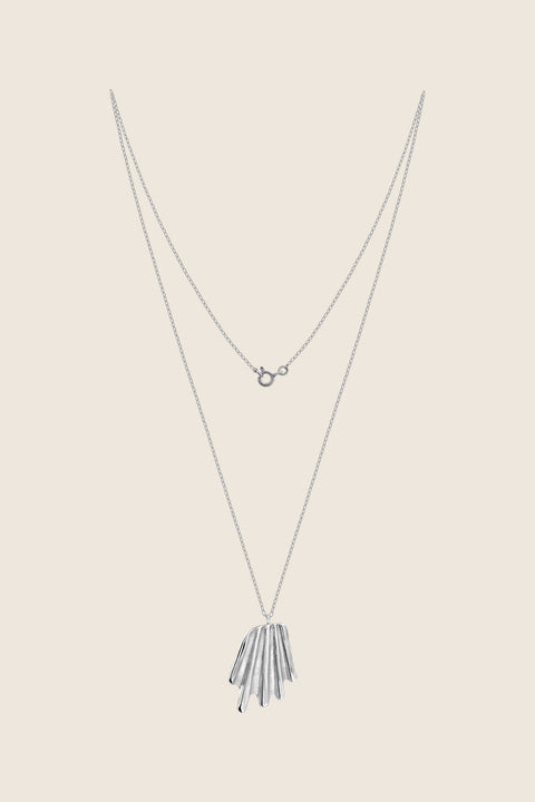A striking pendant inspired by the form of a broken shell, suspended on a 50 cm silver chain. Its sculptural, dynamic shape makes it a bold yet elegant accent for summer looks. Designed for those who appreciate marine motifs in an unconventional, refined form. Discover expressive seaside design by UMIAR jewelry.