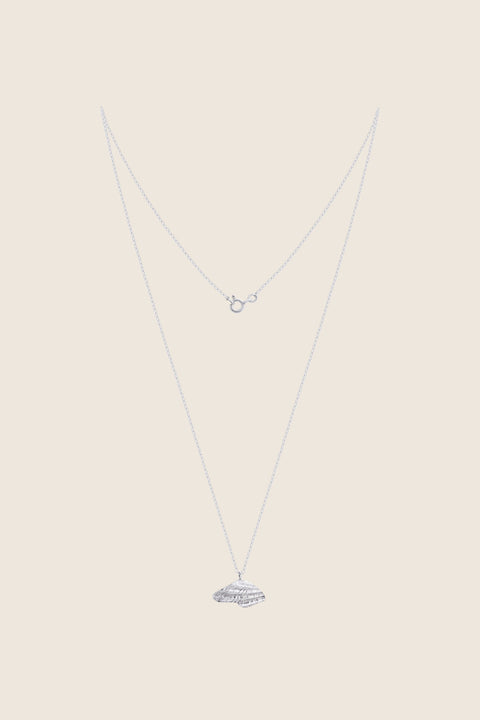 A delicate pendant inspired by the form of a broken shell, measuring 10 x 20 mm and suspended on a 40 cm chain. Combining organic texture with minimalist abstraction, this necklace captures timeless marine elegance. Ideal for summer looks and layering with the MARE II pendant. Discover refined seaside design by UMIAR jewelry.