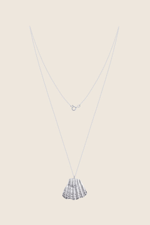 An elegant necklace featuring a large broken shell pendant measuring 25 x 25 mm, suspended on a 50 cm delicate chain. Combining organic texture with minimalist form, it is an ideal accent for summer looks. Beautiful worn alone or layered with the MARE I pendant. Discover refined marine elegance by UMIAR jewelry.
