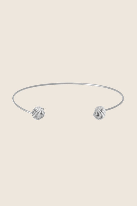 A minimalist choker inspired by the classic torques form, crafted as a rigid half-hoop with realistic shell details. Elegant and contemporary, it highlights the collarbones and adds a refined marine accent to summer looks. Discover modern jewelry with a seaside spirit by UMIAR jewelry.