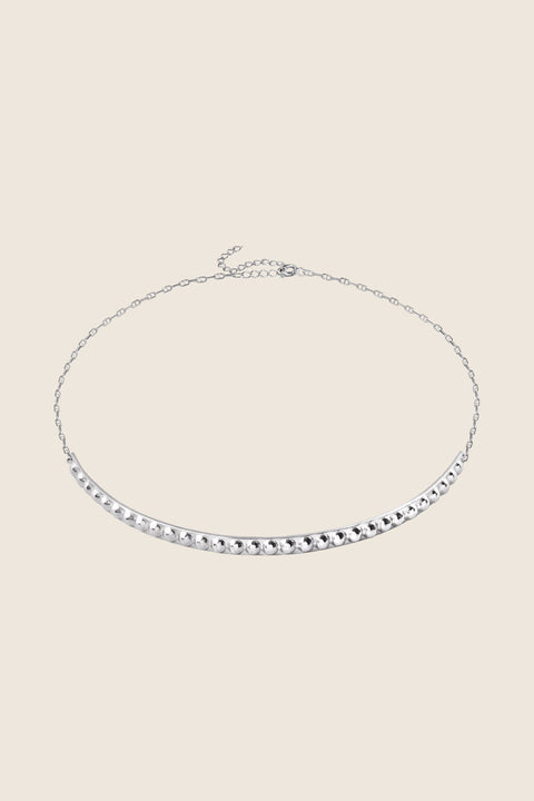 A decorative choker necklace featuring a studded half-hoop and adjustable length for a perfect fit. Elegant yet flirtatious, it highlights the neck and décolletage with refined character. With a total length of 40 cm, it adapts effortlessly to various styling needs. Discover expressive elegance by UMIAR jewelry.
