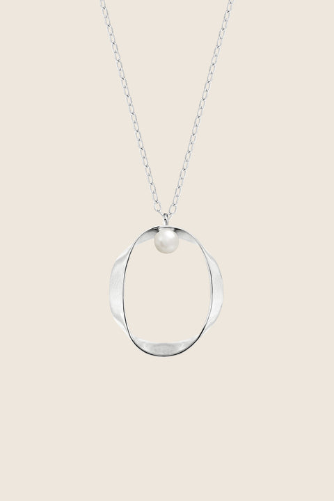 A minimalist pendant inspired by feminine intimacy, crafted from a sculptural silver ribbon and accented with a natural pearl. Suspended on a 50 cm silver chain, this refined design celebrates the beauty of the body through symbolic form and artistic craftsmanship. Discover expressive minimalism by UMIAR jewelry.