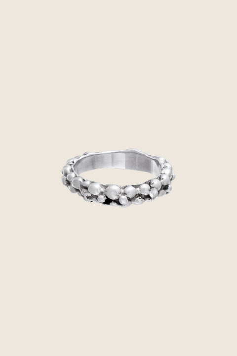 A textured band ring inspired by the sculptural surface of the moon, featuring a granulated, speckled silver finish. Elegant yet subtle, it complements both organic and minimalist jewelry styles. A distinctive everyday piece with a refined edge. Discover lunar-inspired design by UMIAR jewelry.