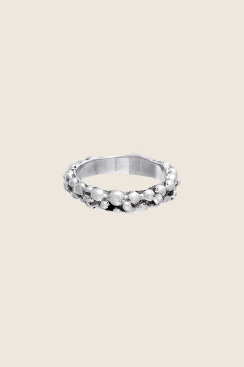 A textured band ring inspired by the sculptural surface of the moon, featuring a granulated, speckled silver finish. Elegant yet subtle, it complements both organic and minimalist jewelry styles. A distinctive everyday piece with a refined, celestial edge. Discover lunar-inspired design by UMIAR jewelry.