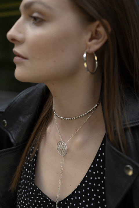 A decorative choker necklace featuring a studded half-hoop and adjustable length for a perfect fit. Elegant yet flirtatious, it highlights the neck and décolletage with refined character. With a total length of 40 cm, it adapts effortlessly to various styling needs. Discover expressive elegance by UMIAR jewelry.