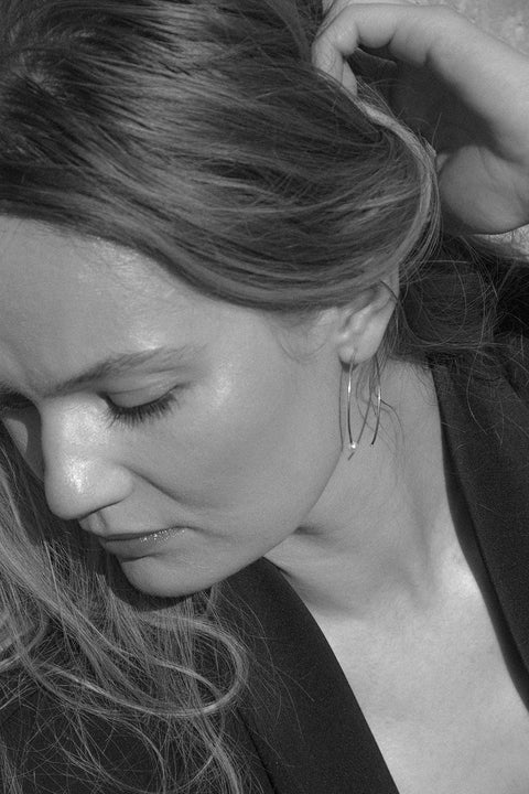 Large minimalist hoop earrings made from fine wire and accented with a natural pearl. Featuring a 45 mm diameter and a thread-through design with no clasp, they offer a refined yet expressive look. A modern statement piece perfect for special occasions. Discover contemporary elegance by UMIAR jewelry.