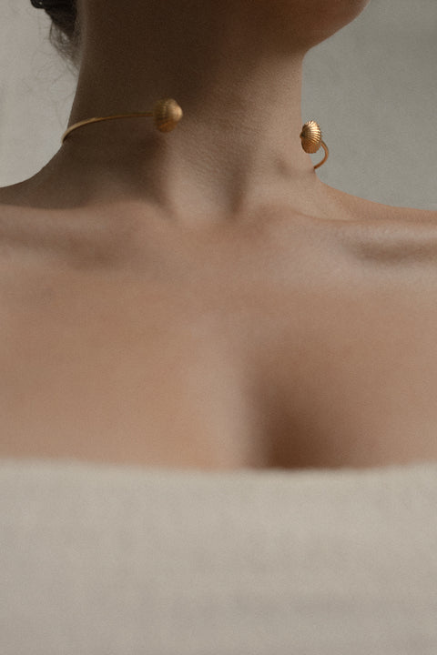 A minimalist choker inspired by the classic torques form, crafted as a rigid half-hoop with realistic shell details. Elegant and contemporary, it highlights the collarbones and adds a refined marine accent to summer looks. Discover modern jewelry with a seaside spirit by UMIAR jewelry.