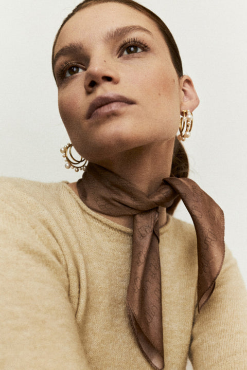 Discover the silk scarf with an original UMIAR Jewellery design. Its caramel-brown colour palette adds a touch of elegance. Crafted from 100% silk twill, this unique scarf makes a perfect, beautifully packaged gift. Experience the blend of thoughtful design and refined craftsmanship in UMIAR’s distinctive creations.
