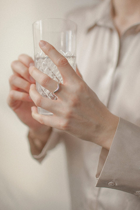 An elegant band ring with a fluid shape that shifts from a straight form into a gentle wave, symbolizing life and emotional flow. A UMIAR bestseller, it blends classic minimalism with subtle movement—perfect as a modern wedding band or an everyday essential. Discover timeless design with meaning by UMIAR jewelry.