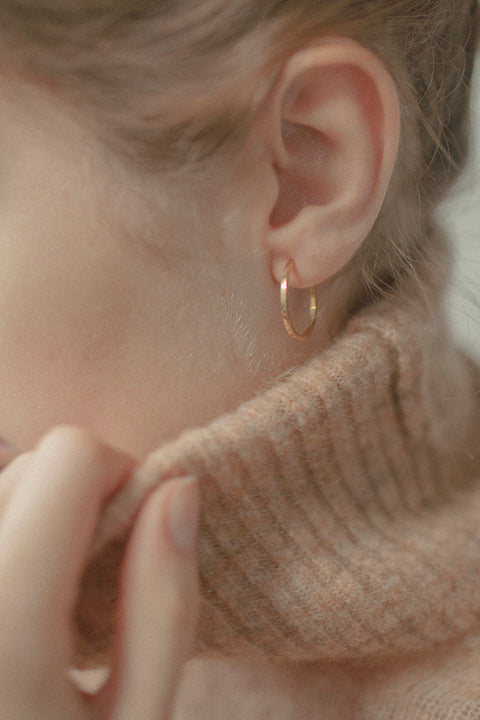 Delicate square-profile hoop earrings with a modern geometric character. Featuring a 23 mm diameter, they bring a contemporary edge to a classic form and can be worn alone or layered with ACTA MICRO. A timeless everyday essential. Discover refined minimalism by UMIAR jewelry.