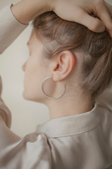 Hoop earrings with a distinctive evolving texture that shifts from hammered to smooth, polished finish. Featuring a bold 45 mm diameter, they offer an expressive yet elegant accent that enhances both minimalist and statement styling. Discover refined craftsmanship and modern design by UMIAR jewelry.