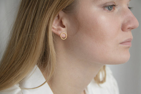 Minimal circle stud earrings set flat against the ear, designed for effortless everyday wear. With a 10 mm diameter, they suit business, casual, and sporty looks alike. A subtle yet distinctive detail that adapts to the ear’s natural geometry. Discover refined simplicity by UMIAR jewelry.