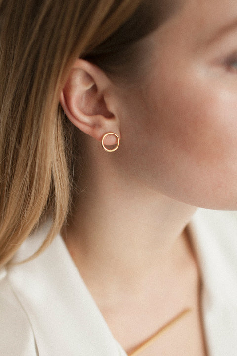 Minimal circle stud earrings set flat against the ear, designed for effortless everyday wear. With a 10 mm diameter, they suit business, casual, and sporty looks alike. A subtle yet distinctive detail that adapts to the ear’s natural geometry. Discover refined simplicity by UMIAR jewelry.