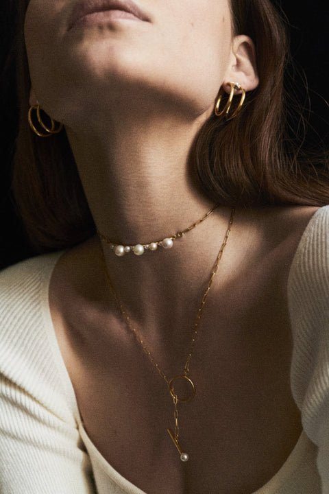 An exceptionally striking choker necklace from UMIAR Jewellery, showcasing a beautiful variety of natural pearls, a delicate chain, and an asymmetrical circular pendant. Handcrafted with care, it is available in both 925 sterling silver and 24k gold-plated sterling silver. This blend of design and craftsmanship creates a unique piece of jewellery that radiates elegance and style.