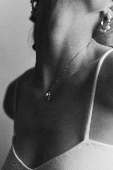 An elegant necklace from UMIAR Jewellery featuring a unique wave-monogram form that gently frames a delicate natural pearl. Handcrafted in 925 sterling silver and 24k gold-plated 925 silver, it radiates refined style and meticulous craftsmanship. Every element of this design blends inspiration with artisanal precision, creating a distinctive piece that complements any look.