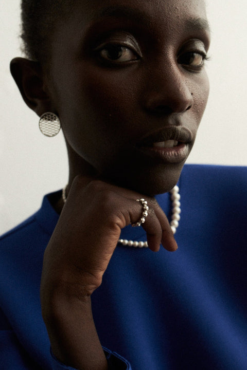 Discover the elastic jeweller’s-cord ring by UMIAR Jewellery, crafted from round beads and delicate rock crystals. Subtle and elegant, it adjusts perfectly to the finger, making it a refined accent for any look. Handcrafted with care, available in 925 sterling silver and 24k gold-plated 925 silver. Order now and add a touch of sophistication to your collection!