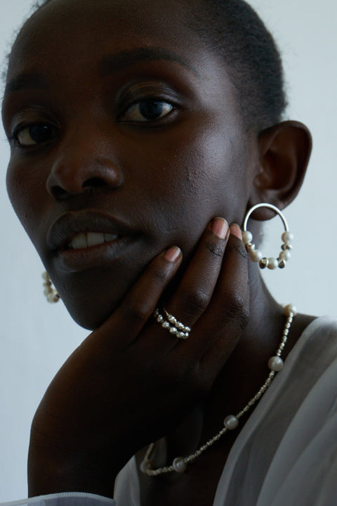 Discover the elastic jeweller’s-cord ring by UMIAR Jewellery, crafted from round beads and delicate rock crystals. Subtle and elegant, it adjusts perfectly to the finger, making it a refined accent for any look. Handcrafted with care, available in 925 sterling silver and 24k gold-plated 925 silver. Order now and add a touch of sophistication to your collection!