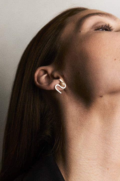 UMIAR Jewellery presents elegant stud earrings in the form of a wave-inspired monogram embracing a natural pearl. Their distinctive design catches the eye and adds a refined touch to any look. Each pair is handcrafted from high-quality materials: 925 sterling silver and 24k gold-plated 925 silver. A design where craftsmanship meets creativity, and inspiration transforms into creation.